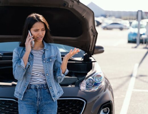 Woman standing next to her broken car