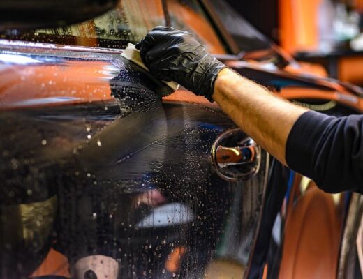 a man's hand waxes the surface of a car